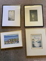 Four art prints framed and laid flat on carpet. Varied sizes and styles, mostly natural themes and landscape scenes.