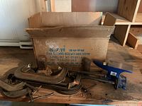 Photo showing a group of five large metal C-clamps and a blue swivel base bench vise next to the original labeled cardboard box.
