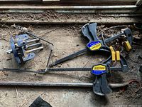 Photo of the bench vise, two Quick-Grip clamps, and crowbar together on the ground showing overall condition and size relative to each other.