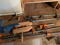 Wide view of all clamps and bench vise on wooden surface showing condition and sizes