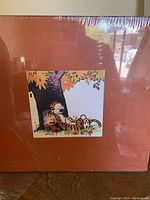 Front of shrinkwrapped slipcase featuring Calvin and Hobbes illustration beneath a tree