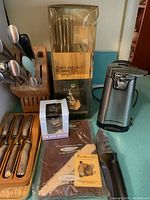 Photo showing wooden knife block with StaySharp brand knives, a wooden steak knife holder with knives, electric can opener, and kitchen timer on a countertop.