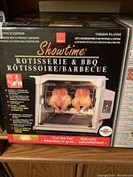 Front view of Showtime Platinum Edition Rotisserie & BBQ box showing product image, branding, and key features including 'Cut the Fat' cooking claim.