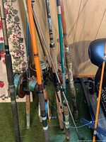 Photo showing a cluster of seven fishing rods with some reels attached, various colors and handle materials.