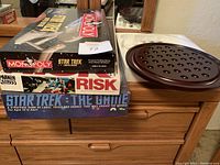 Stacked boxed board games: Star Trek Monopoly Limited Edition, Risk, Star Trek The Game with wooden marble solitaire board with glass marbles on side