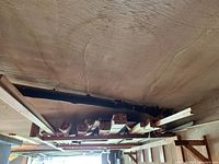 View of vertical storage rack with multiple bundles of wooden trim lumber tied together, assorted sizes and lengths visible.