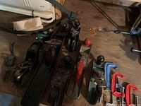 Eight hand planes and four C-clamps arranged on workbench