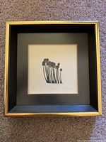 Front view of framed black and white abstract print with black matte and gold frame.