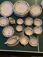 Full overview of the Burgundy pattern china set showing all plates, cups, saucers, platters, gravy boat, and milk jug arranged on table.