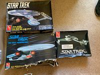 Three damaged Star Trek model kit boxes visible: Special Edition U.S.S. Enterprise with lights and sound, The Next Generation U.S.S. Enterprise, and Klingon Cruiser model kits.
