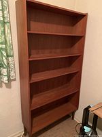 Full view of the wood bookshelf showing all five shelves and tapered legs.