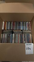 Top view of a full box with multiple rows of CDs in jewel cases, showing a variety of album spines and titles.