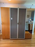 Front view of the three-piece IKEA wardrobe set showing central frosted glass doors and wooden side units with drawers.