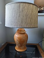 Full view of orange ceramic lamp with fabric drum shade on and off