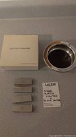 Silver wine bottle coaster and four place card holders displayed on a countertop showing the item box and handwritten label.