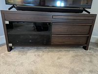 Full view of TV stand showing dark wood finish, two drawers on the right, and glass door on the left.