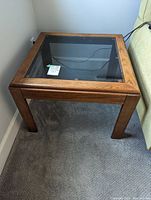 Side view of a square wood and glass side table showing the wood grain and leg structure.