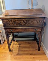 Closed view of medium-tone wood secretary desk with drawer and panel above drawer.