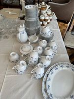 Wide view showing full Mikasa fine bone china set with various plates, cups, saucers, teapot, creamer, and sugar bowl arranged on table beside wooden nut crackers.