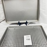 Front view of one sheet pan standing on display stand behind one cooling rack placed flat.