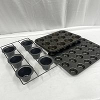 Set of three baking molds including two 24-cup muffin pans and one 6-cup cone mold rack shown on white surface