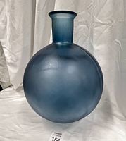 Front view of the large blue frosted glass vase with rounded body and narrow neck, placed against a white fabric background.