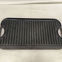 Top view of the cast iron rectangular reversible grill surface with grill ridges and handles on each side.