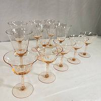 Ten pink optic panel depression glass cordial glasses, six taller with narrow bowls and four shorter with wide bowls, arranged on white surface.