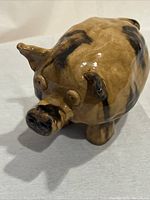 Front and side view of handmade ceramic pig figurine with mottled brown and black glaze.
