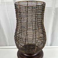 Front view of Rickma distressed candleholder showing woven metal globe in antiqued gold leaf on a chestnut brown wood base.