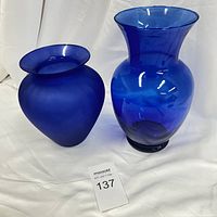 Two cobalt blue glass vases displayed side by side, showing size and shape differences