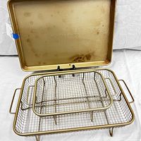 Nonstick baking sheet and two wire baskets nested inside, showing usage wear and branding.