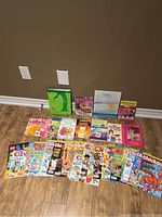 Photo showing the entire lot with various kids books and magazines arranged on the floor against a wall, including colorful covers and multiple issues of Chickadee magazine.