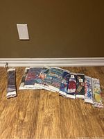 Full view of the 10 diamond art craft project kits in their original packaging, arranged side by side on wood floor.