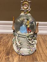 Front view of Disney Cinderella snow globe showing Cinderella and Prince Charming dancing inside with detailed castle base and flowers.