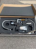 Full view of the chrome kitchen faucet with extendable feature inside box with foam cushioning.