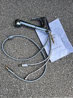 Full view of the chrome finish faucet with attached flexible hoses and installation instructions beneath it.