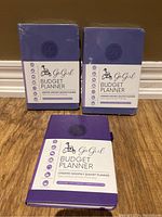 Three purple GoGirl Budget Planners shown together, two sealed and one unwrapped