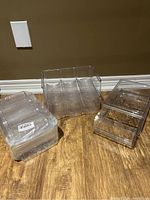 Photo of three clear plastic organizers on wooden floor, two are stacked and one is in packaging.
