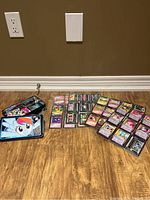 Full lot viewed against a wall showing the tin box, pages with cards, and loose cards spread on the floor.