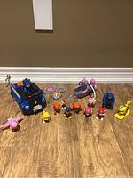 Wide shot showing all Paw Patrol toys including vehicles, figures, and accessories on wooden floor.