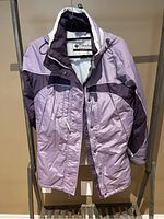 Front view of purple women's Columbia coat hanging, showing full zip and snap front closure with pockets.