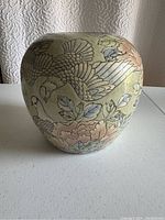 Front view of the vase showing a flying bird with outstretched wings and surrounding flowers in pastel colors