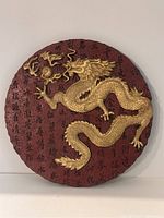 Front view of the round decorative Asian dragon plate showcasing the gold dragon relief over a red textured background with Asian characters.