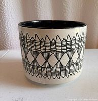 Side view of the ceramic planter showing black and white geometric pattern on the exterior.