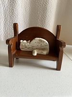 Front angle of wooden sofa with white carved cat lying curled up, showing detail and finish