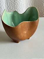 Brown exterior with aqua interior ceramic bowl, showing wavy rim and feet.