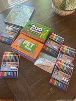 Overview of kids step-by-step art card sets, multiple dual tip marker packs, and a small pack of stickers, displayed on a wooden table.