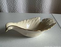 Side angle view of the Lenox bird-shaped candy dish showing its sculpted bird form, feather ridges and gold trim along the rim.