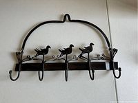 Front view of handmade metal bird hanger with 5 hooks, black finish, showing three birds perched on branch design and curved top